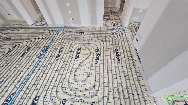 Plancher chauffant hydraulique dans une pièce de vie de maison neuve avec grandes ouvertures